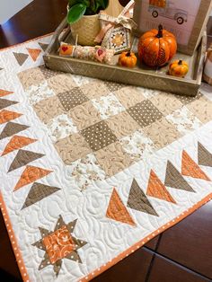 a quilted table topper with pumpkins and other decorations on it, sitting on a dining room table