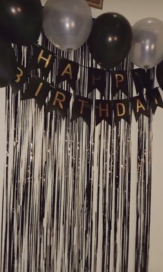 black and silver balloons hanging from the ceiling with happy birthday banner in front of it