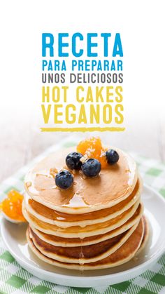 stack of pancakes with blueberries and oranges on top, in front of the words receta para preparar unos delicioos hot cakes veganos