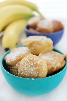 some sugar covered doughnuts in a bowl next to bananas and other food items