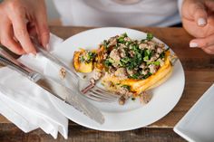 a person is holding a fork and knife over a plate with some food on it