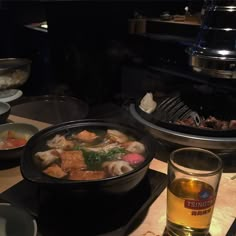 a table topped with lots of food next to a glass filled with liquid and sauce