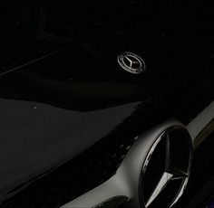 the front end of a black sports car with its hood up and emblem on it