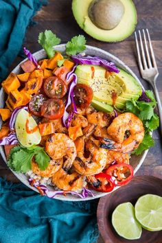 a bowl filled with shrimp and vegetables next to avocado