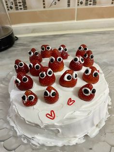 a white cake with strawberries and eyes on it