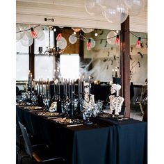 a long table is set up with skeleton decorations and candles for halloween dinnereons