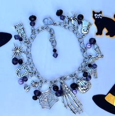 This chunky handmade charm bracelet is a must have for Spooky Season. It has 11 zinc metal alloy charms.  Purple and black bicone and roundelle crystal beads.  PURPLE and black pearls.   (The pearls look lavender in the pictures but they are purple.) The chain is stainless steel so it will not tarnish, it is 7 1/2 inches with an approximate 1 1/2 inch extension chain. Charms Skeleton hand Spider web Cat Vampire fangs Pumpkin Witch on broom Bat Ghost Haunted house 2 - spiders This Halloween charm Nickel Free Black Metal Charm Bracelet, Silver Themed Bracelet For Halloween, Novelty Silver Bracelet For Halloween, Black Metal Charm Bracelet, Halloween Themed Silver Bracelet, Novelty Black Jewelry With Charms, Black Novelty Jewelry With Charms, Halloween Gift Charm Bracelet, Silver Halloween Novelty Bracelet