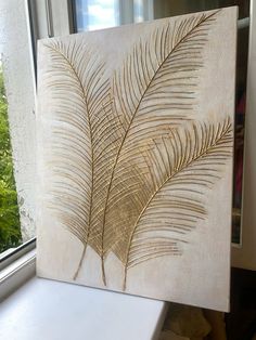 a painting on a window sill with a plant in the background