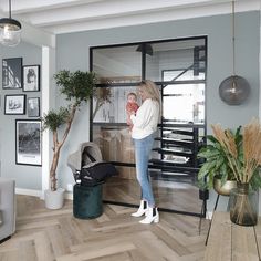 a woman standing in front of a living room filled with furniture and pictures on the wall