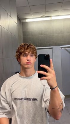 a young man taking a selfie with his cell phone in the bathroom mirror,