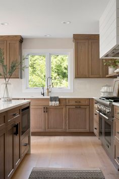 a large kitchen with wooden cabinets and stainless steel appliances, along with an area rug on the floor