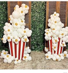 two red and white popcorn buckets filled with balloons