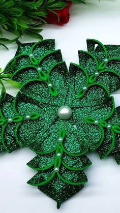 a green brooch sitting on top of a white table next to flowers and greenery