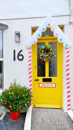 a yellow door with candy canes and wreath on the front entrance to a white house