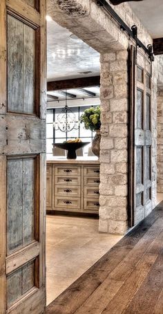 an open door leading to a kitchen and dining room with stone walls, wood floors and exposed beams