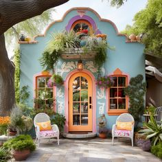 a colorfully painted house with two chairs and potted plants