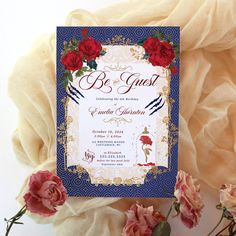 a blue and gold wedding card with red roses on it next to some pink flowers