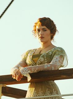 a woman standing on top of a boat next to a sail ship with her arms crossed