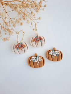 three decorated pumpkins sitting on top of a white table next to some dried flowers