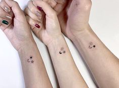 three girls with matching tattoos on their arms holding hands and looking at each other's wrist