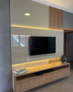 a large flat screen tv mounted to the side of a wooden entertainment center in a living room