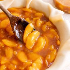 a wooden spoon in a bowl filled with baked beans