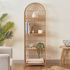 a living room with a rattan book shelf next to a chair and potted plant