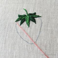 a close up of a piece of cloth with a needle and some green leaves on it