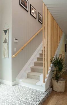 the stairs in this house are made of wood and have pictures on the wall above them