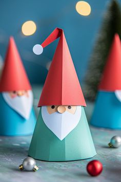 three paper christmas gnomes sitting on top of a table