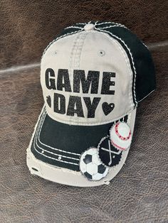 "PLEASE READ:     **FREE SHIPPING on orders of $35+ **This design ships in 3-4 days from the date the order is placed.   Please review all pictures and listing details/options here: STANDARD DESIGN DESCRIPTION: **Black and light grey two-tone adjustable ball cap. **Glitter GAME DAY with hearts on either side **Add up to 6 sports on the bill of the hat **Back of hat has a love heart.  Rhinestones embellish the adjustable closure. ** Up to 6 sports on the bill.  You let me know your sports in the notes at checkout ** On 1 or 2 or 3 sport designs, MOM or a name up to 6 characters will fit on the other side of the bill OPTIONS YOU CHOOSE AT CHECKOUT: Personalization/Customization:   ** No personalization **Name on back of hat.  See below ⬇️ **NAME ON BACK feature is extra $2-$7.  There are 3 o Personalized Baseball Cap For Outdoor, Personalized Snapback Hats For Sports Events, Gray Hat One Size For Sports Events, Personalized Sports Cap, Customizable Adjustable Baseball Cap For Sports Events, Customizable Sports Hat With Curved Bill, Adjustable Hat For Game Day, Baseball Season, Customizable Sports Hat With Curved Brim, Customizable Sporty Baseball Cap