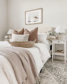 a bed with white sheets and pillows on top of it next to a nightstand in front of a window