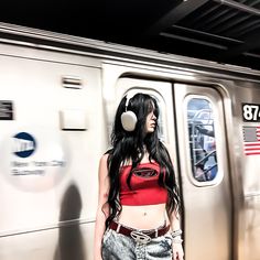 a woman with headphones standing in front of a train