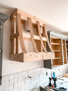 a kitchen with wooden shelves hanging from the ceiling and cabinets on the wall behind it