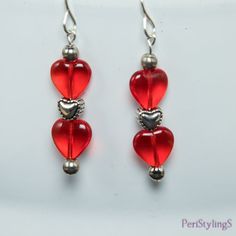 two red heart shaped glass beads hanging from silver earwires on a white background