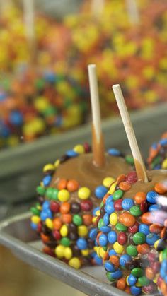 chocolate covered candy apples with sprinkles and sticks sticking out of them on a tray