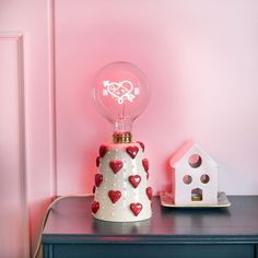 a lamp that is on top of a table next to a small house and birdhouse