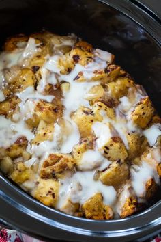 a crock pot filled with cinnamon rolls and cream cheese sauce on top of it