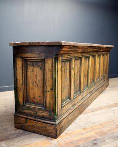 an old wooden cabinet sitting on top of a hard wood floor next to a wall