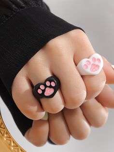 a woman's hand with pink and white paw prints on it, holding a black ring