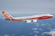 an orange and white airplane flying over the clouds