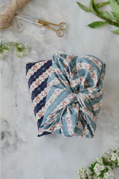 a blue and white flowered bow on top of a marble table next to scissors