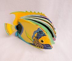 a yellow and blue fish shaped bookend sitting on top of a white tablecloth