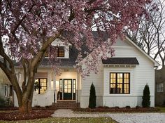 a white house with pink flowers on the trees