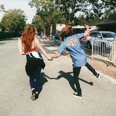 two people holding hands while walking down the street