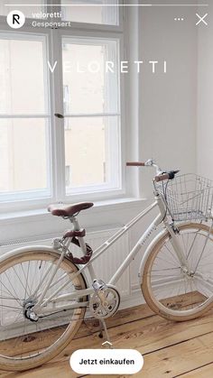 a white bicycle parked in front of a window next to a wooden floor and wall