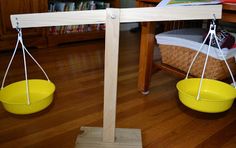 two yellow bowls are suspended from the ceiling in front of a wooden table and bookshelf