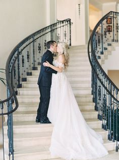 a bride and groom kissing in front of the stairs at their wedding reception on the grand staircase