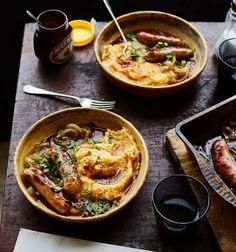 two bowls filled with food on top of a wooden table next to drinks and utensils