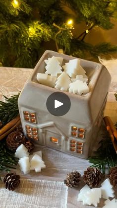 a small house made out of clay surrounded by pine cones and cinnamon sticks